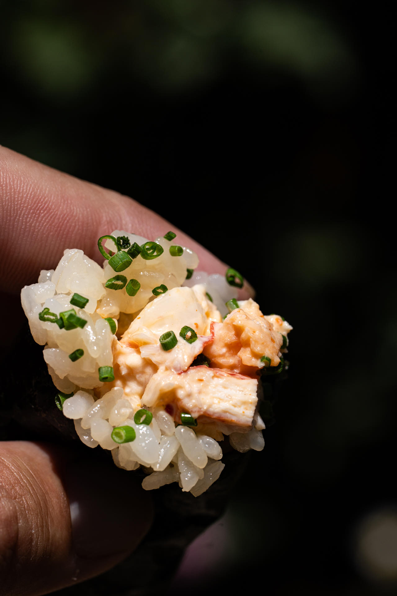 Crab and chive hand roll held up to the camera